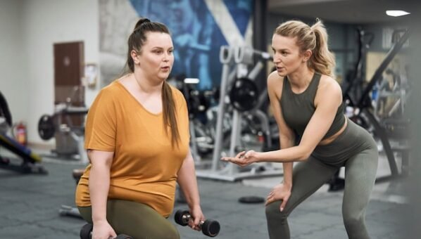 [freepicdownloader.com]-caucasian-plus-size-woman-with-her-trainer-working-out-gym-normal